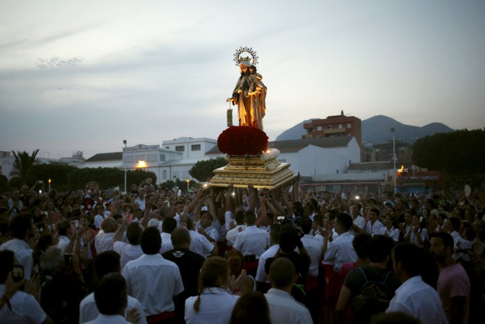 Men in traditional costumes carry a statue of the El Carmen Virgin, on its way to be carried into the sea, during a procession in Malaga