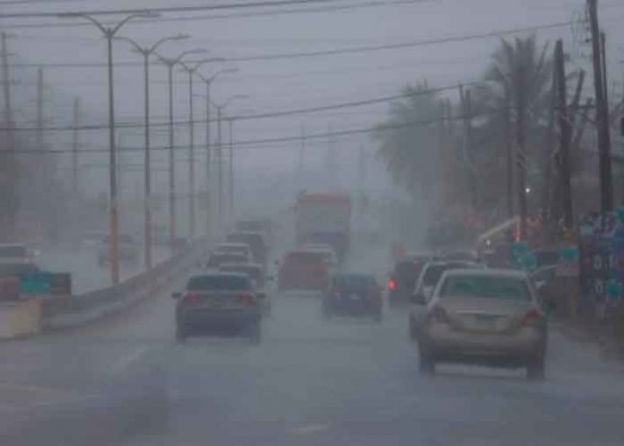 Carros transitan hoy por la Carretera 2 en plenas lluvias y entre la alerta por la posible tormenta tropical Fred, en Vega Alta / EFE/ Thais Llorca /