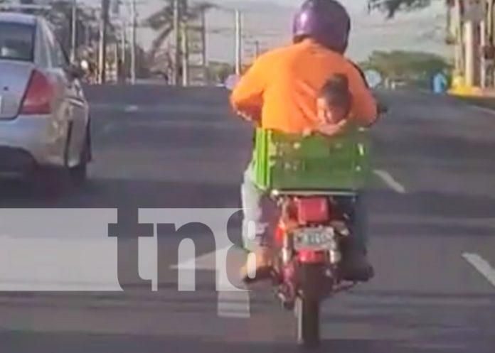  Momento en que un motorizado lleva a una niña en una cajilla, a bordo de una moto, en Managua 