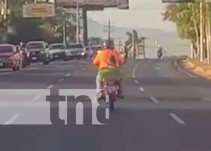 Momento en que un motorizado lleva a una niña en una cajilla, a bordo de una moto, en Managua