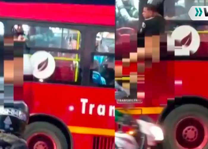 Desnudo y colgado de la ventana de un bus